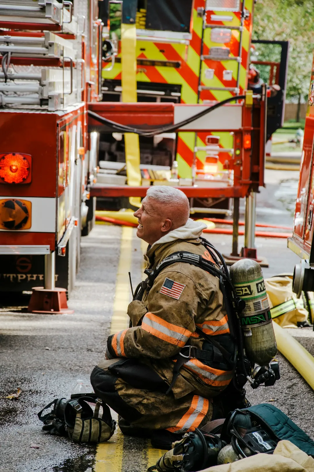 A firefighter kneeling beside a fire truck